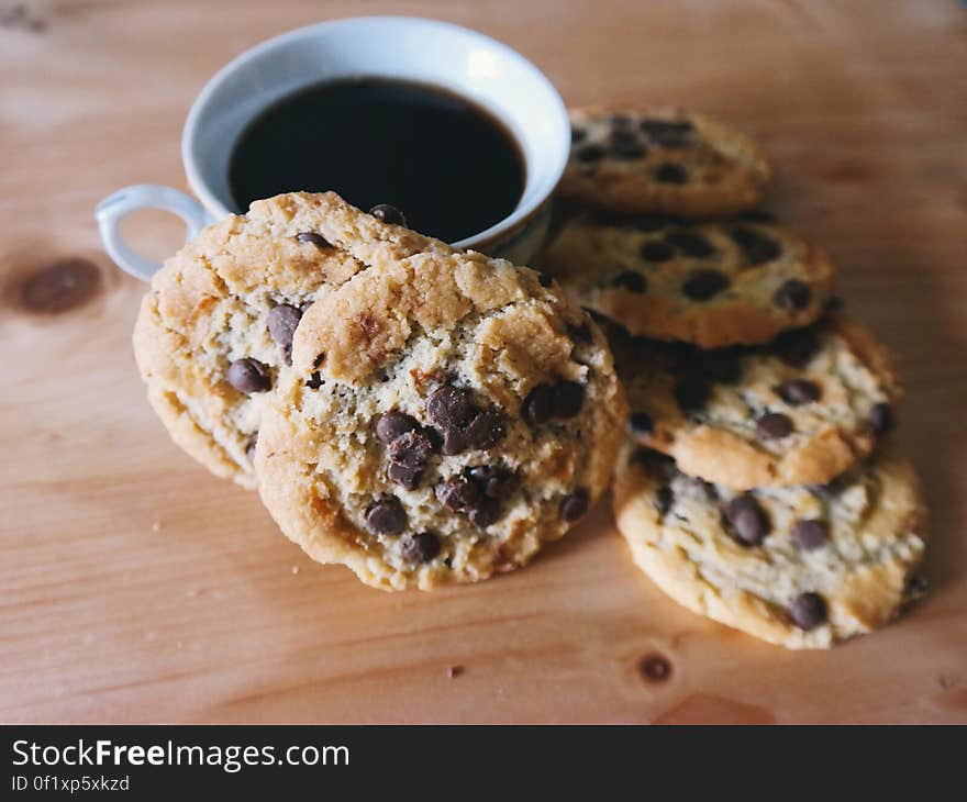 A close up of a cup of coffee and chocolate chip cookies. A close up of a cup of coffee and chocolate chip cookies.