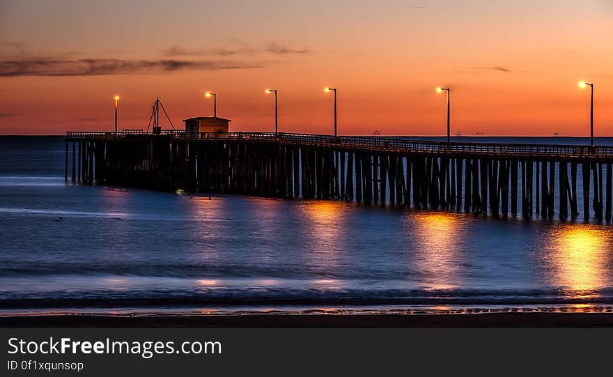 Wooden Dock on Sea Shore With Light Post during Sunset