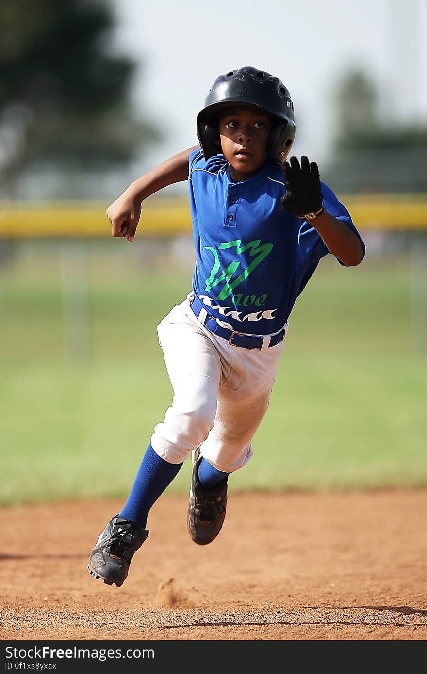 Boy in Blue and White Baseball Jersey Running on Brown Soil Field during Daytime