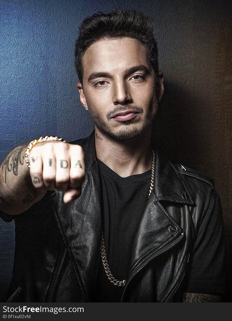 A portrait of J Balvin showing his right fist with vida tattoo on it. A portrait of J Balvin showing his right fist with vida tattoo on it.