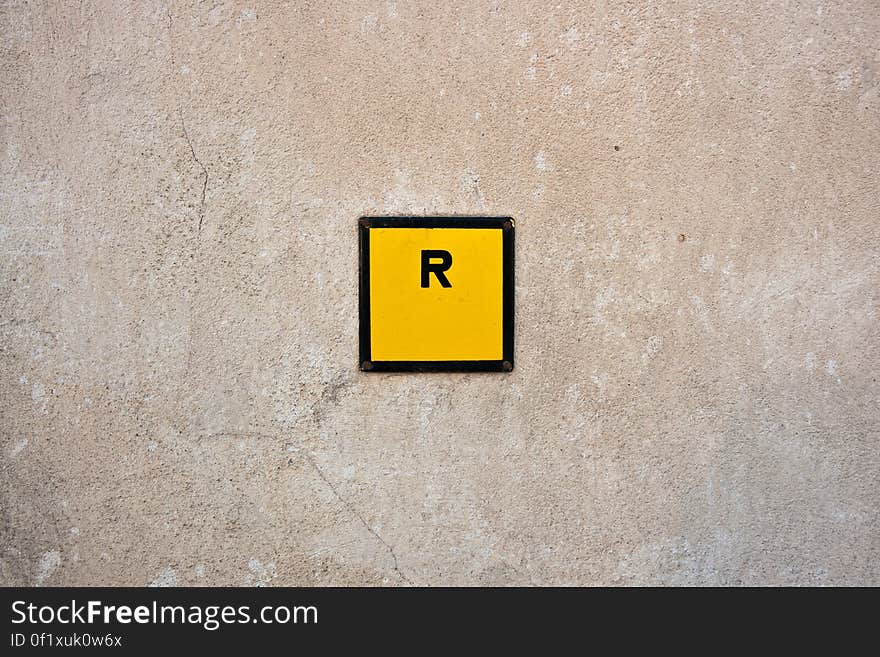 An R sign in a yellow square on a wall. An R sign in a yellow square on a wall.