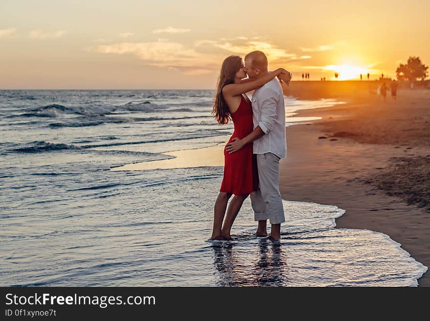 Romantic barefoot couple kissing on beach at sunset. Romantic barefoot couple kissing on beach at sunset.