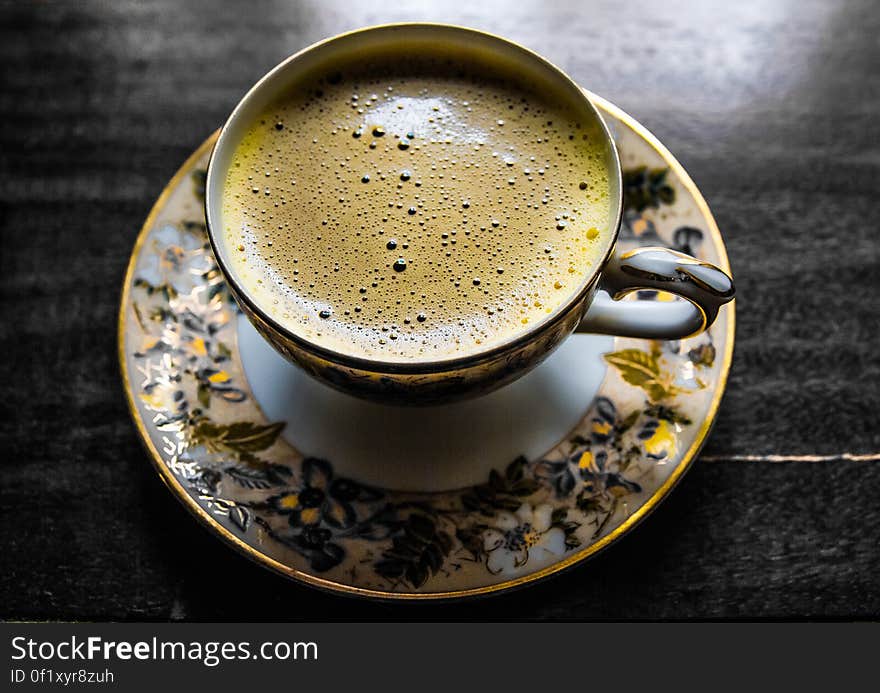 Elevated view of cup of coffee on porcelain saucer.