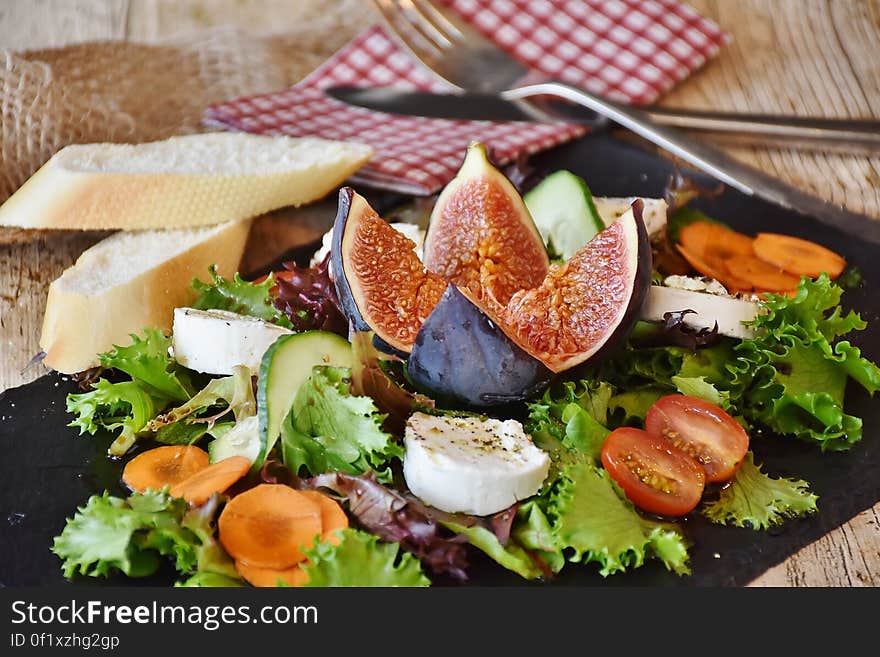 Fresh salad, cheese and bread on chopping board with cutlery and napkin. Fresh salad, cheese and bread on chopping board with cutlery and napkin.