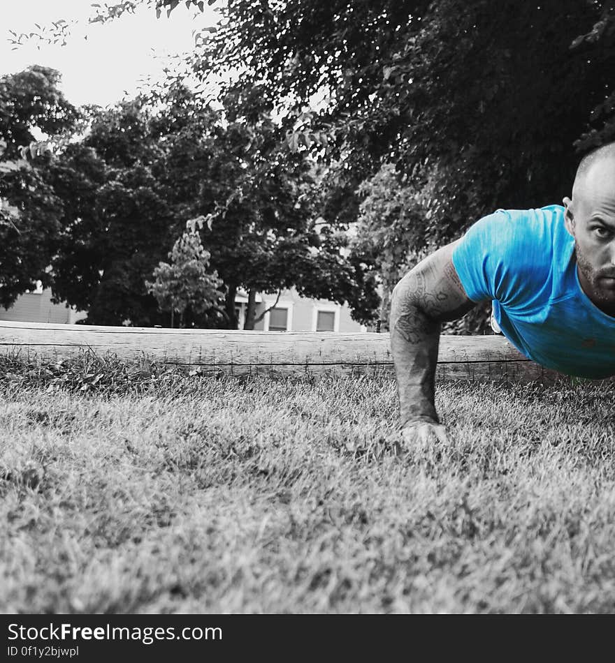 A man doing push ups on grass, selective color filter.