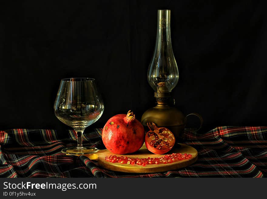 Ripe pomegranate fruit on table with whisky glass and retro style lamp. Ripe pomegranate fruit on table with whisky glass and retro style lamp.