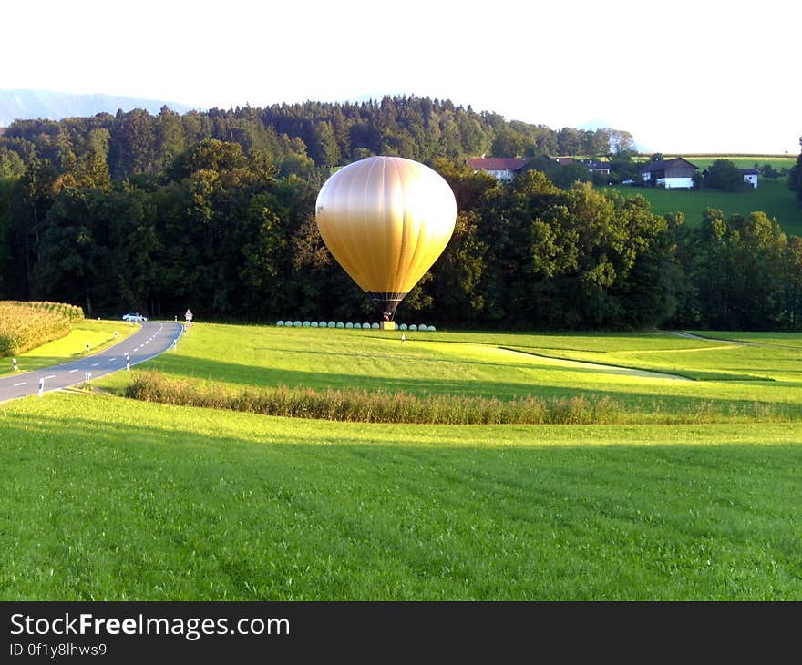 A golden hot air balloon above a green field.