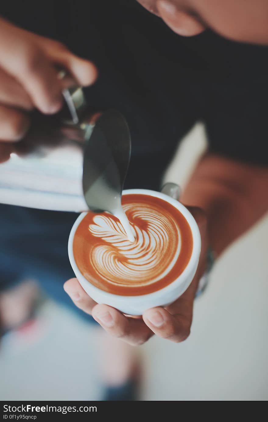 A barista making a cup of coffee with latte art with milk foam. A barista making a cup of coffee with latte art with milk foam.