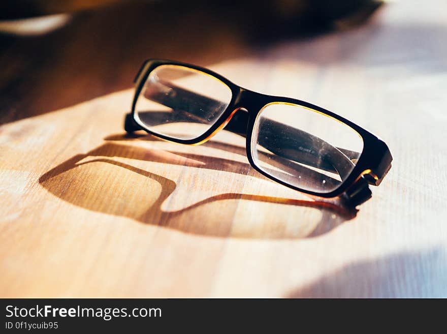 A pair of eyeglass on a table casting a shadow. A pair of eyeglass on a table casting a shadow.