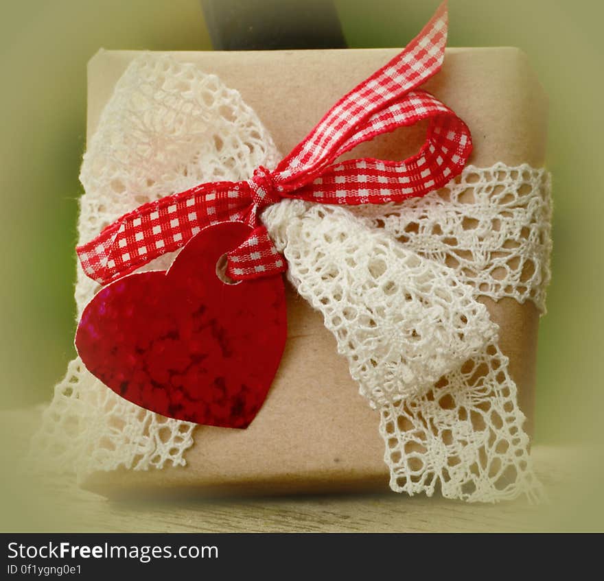 A gift box with an embroidered and plaid bow and a heart.