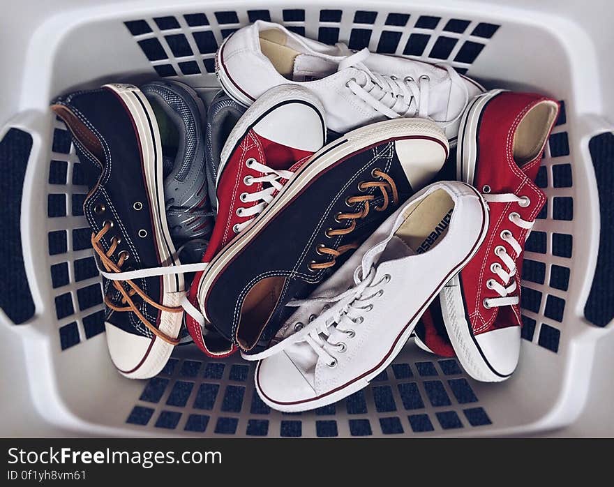 A white plastic basket with canvas sneakers. A white plastic basket with canvas sneakers.