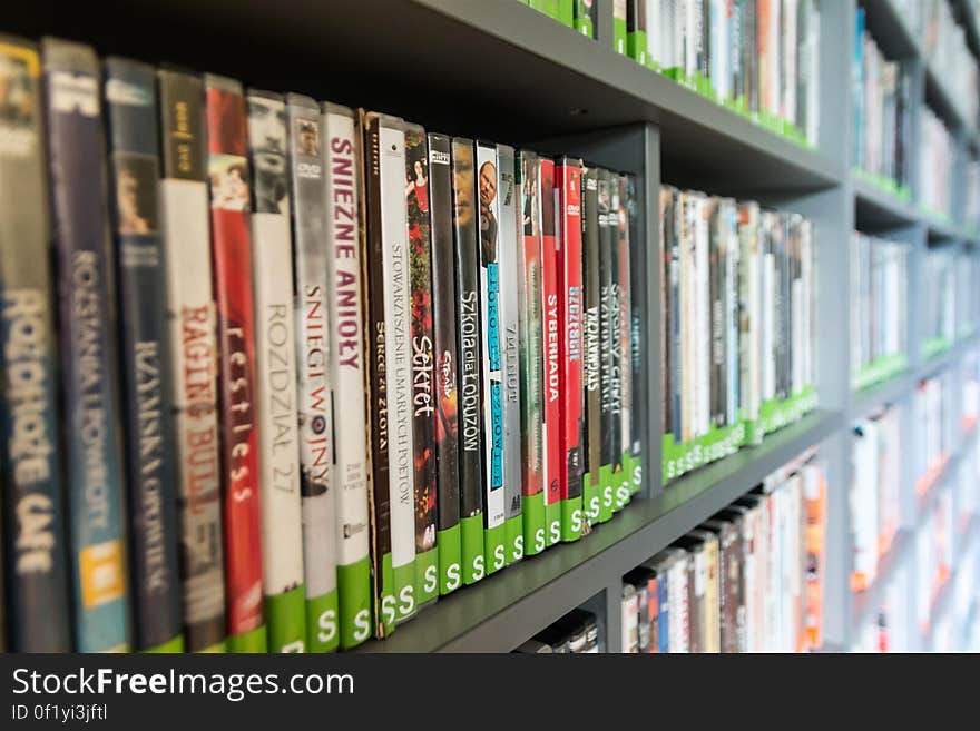 A collection of DVD cases for movies in a bookshelf or a library. A collection of DVD cases for movies in a bookshelf or a library.