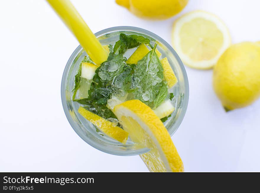 A drink with lemon and mint leaves in a glass.