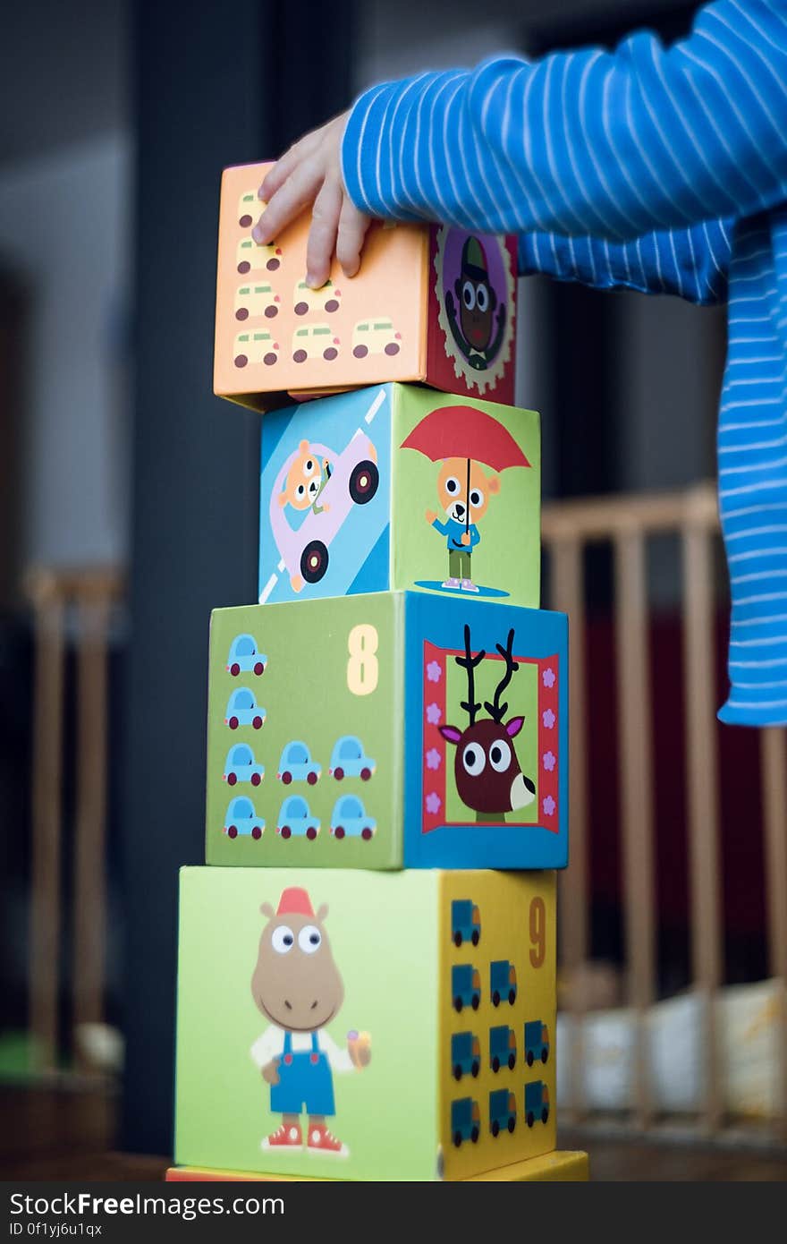 A child building a tower from colorful toy blocks. A child building a tower from colorful toy blocks.