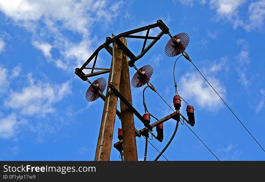 An overhead power line attached to a wooden pole.