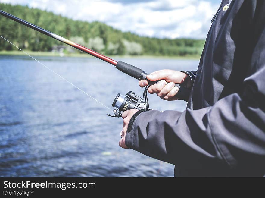 A person fishing with an open reel fishing pole.