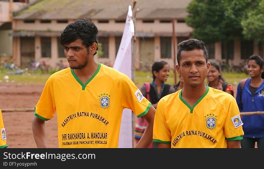 Soccer players in yellow jersey's standing outdoors.