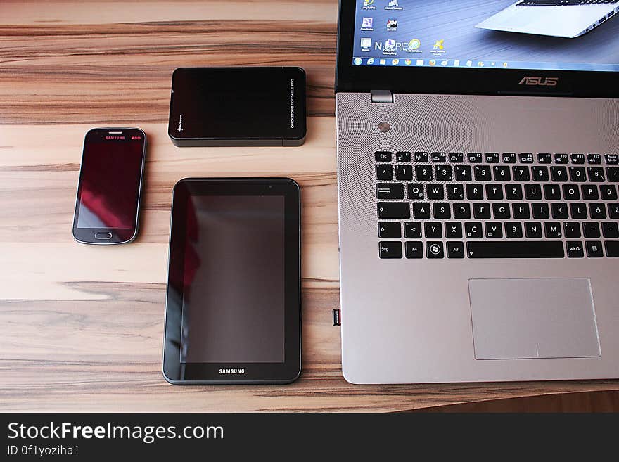 Various electronic devices on desk, laptop, tablet, mobile phone.