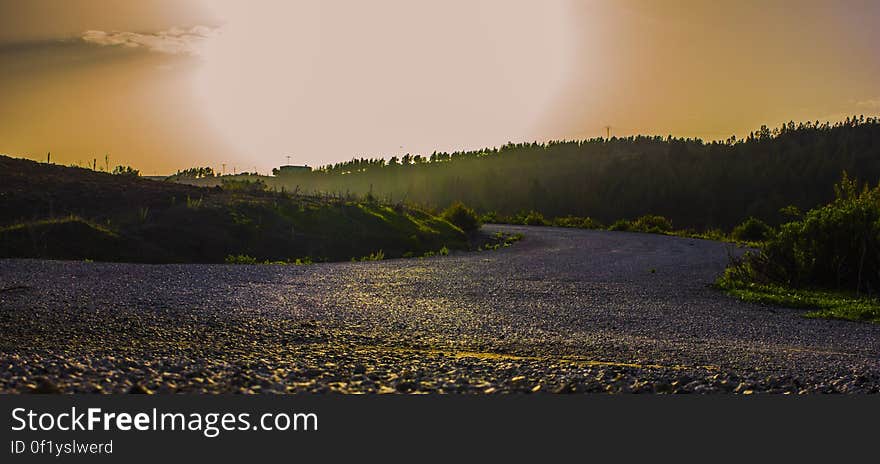 A road passing through landscape under bright sunlight. A road passing through landscape under bright sunlight.