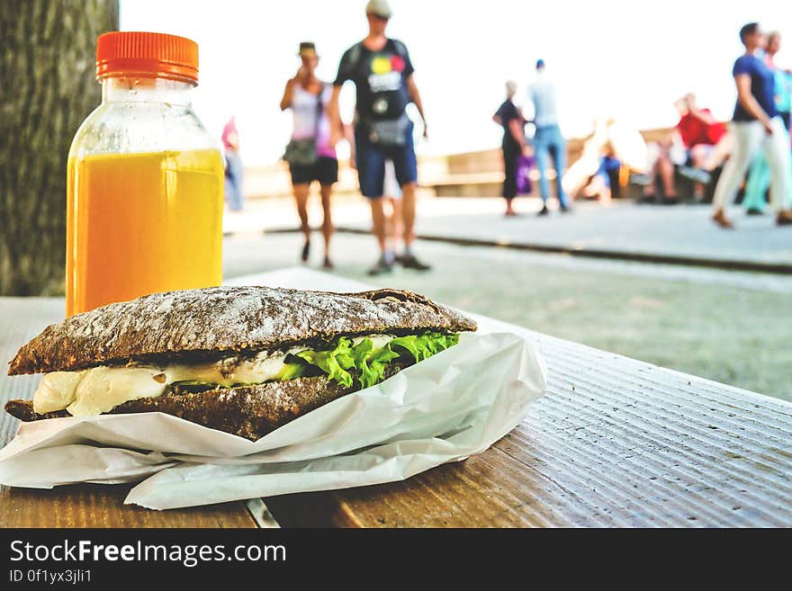 A sandwich and orange juice on a table outdoors. A sandwich and orange juice on a table outdoors.