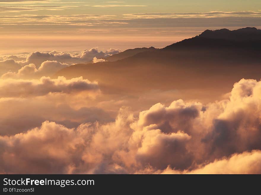 Silhouette of Mountain With Fluffy Clouds during Sunset