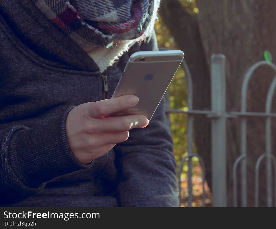 A person checking their mobile phone outdoors in the autumn. A person checking their mobile phone outdoors in the autumn.