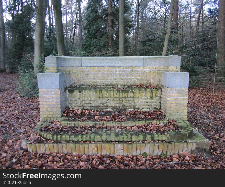 Empty flower bed with protective brick walls covered by fallen Autumn leaves, background of tall trees. Empty flower bed with protective brick walls covered by fallen Autumn leaves, background of tall trees.