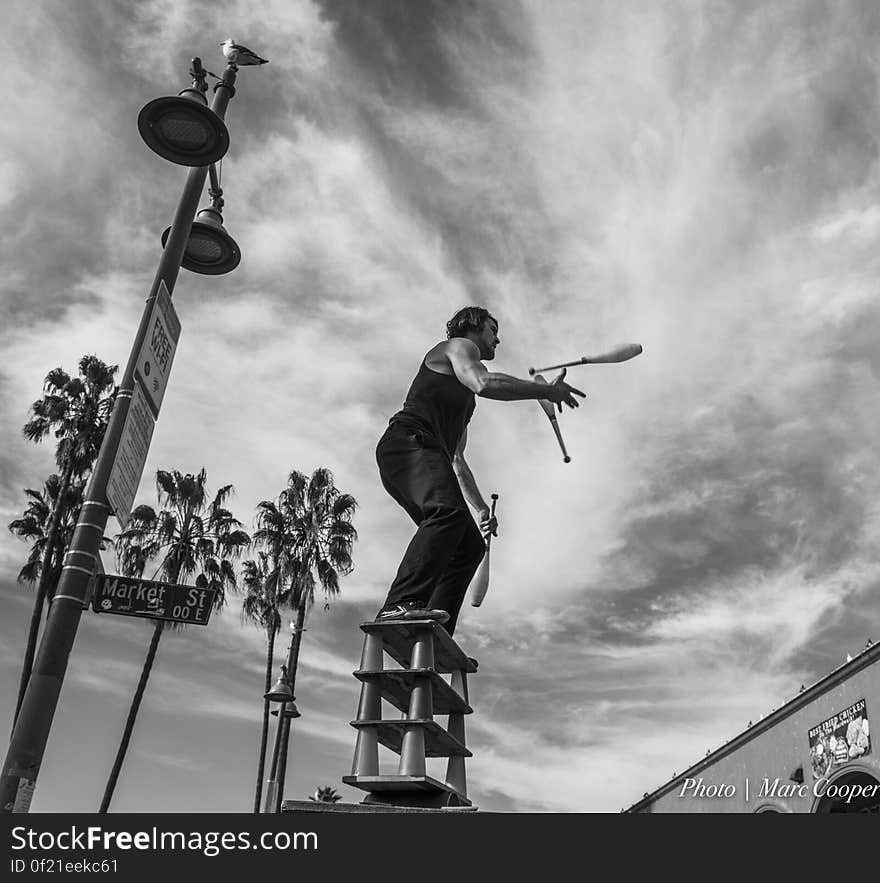 Street Acrobat juggles atop 12 glasses and an aluminum roller. On the boardwalk in Venice Beach California. Street Acrobat juggles atop 12 glasses and an aluminum roller. On the boardwalk in Venice Beach California