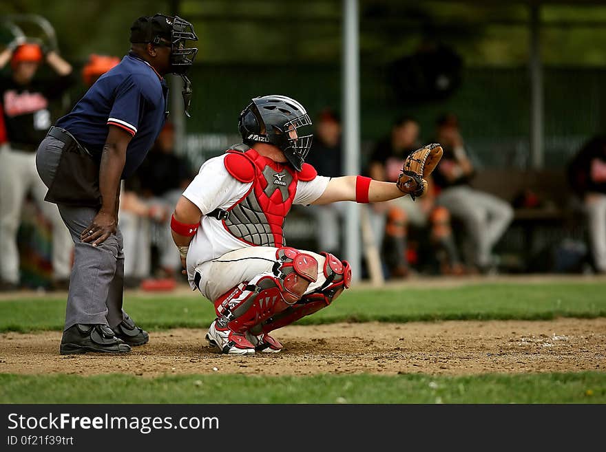 White and Red Baseball Player With Black Face Helmet and Brown Leather Mitts