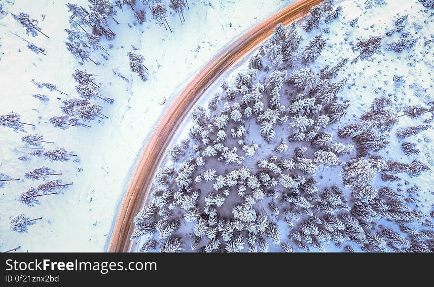 An aerial view of a road next to an evergreen forest in winter. An aerial view of a road next to an evergreen forest in winter.