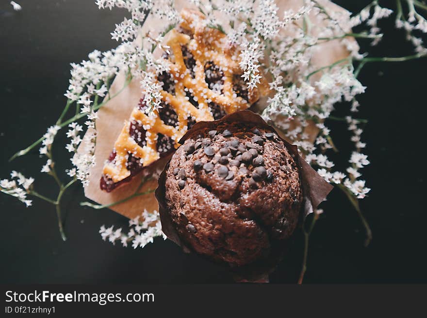 A chocolate cupcake and a slice of pie with wild flowers. A chocolate cupcake and a slice of pie with wild flowers.