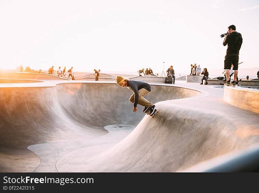 A group of skateboarders in a skate park with a photographer photographing a skater in a bowl. A group of skateboarders in a skate park with a photographer photographing a skater in a bowl.