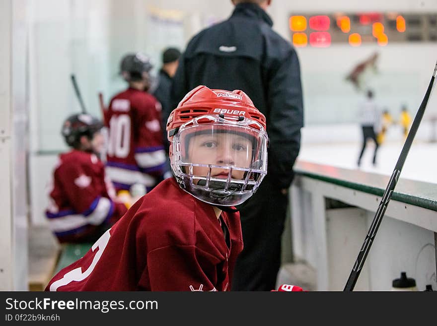 Youth hockey player in safety equipment on bench during game.