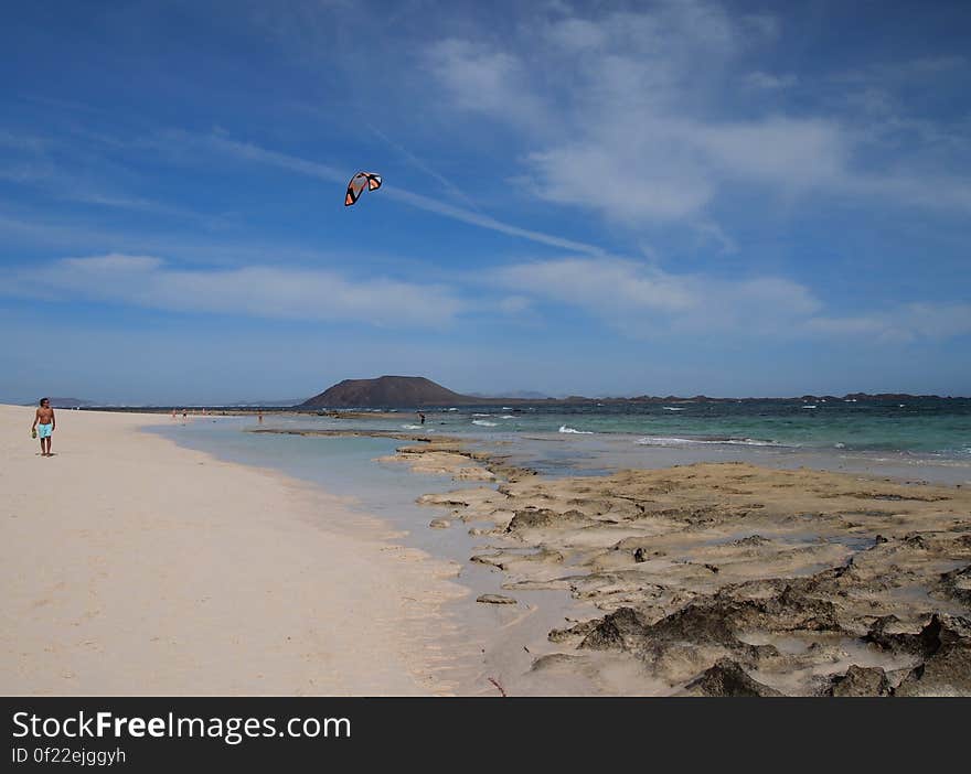 A man flying a kite above a sandy beach. A man flying a kite above a sandy beach.