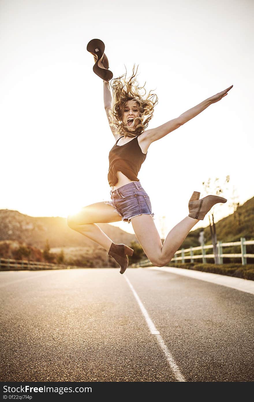 A woman jumping in the air on a highway. A woman jumping in the air on a highway.