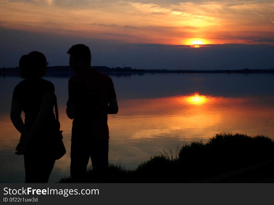 Silhouette of Man and Woman Near Water during Sun Set