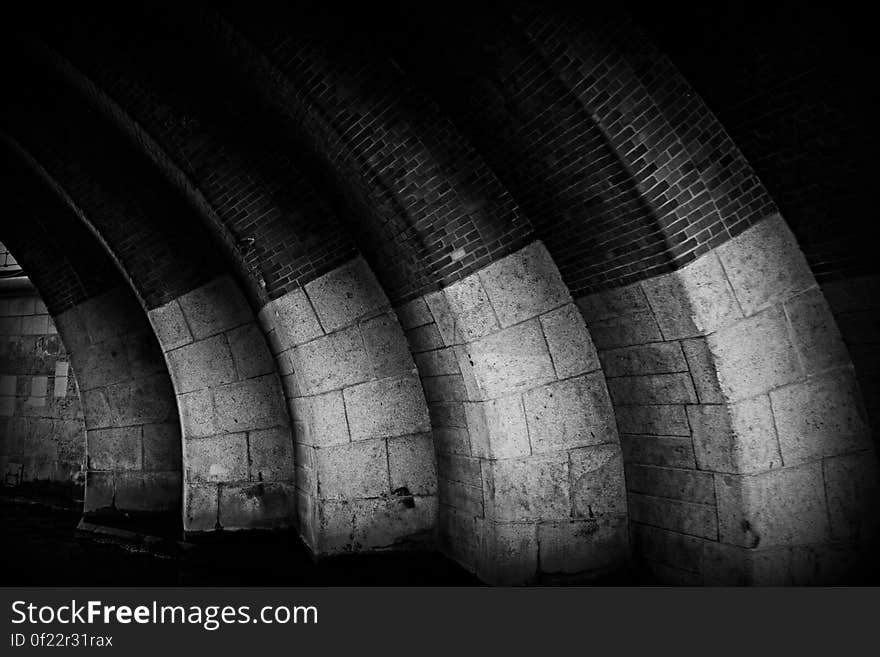 A black and white photo of arches made of stone and brick. A black and white photo of arches made of stone and brick.