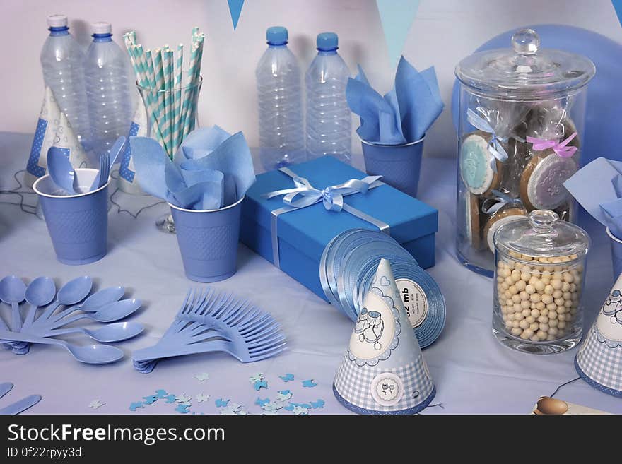 A birthday table setting with blue-colored items, utensils, cups and party items. A birthday table setting with blue-colored items, utensils, cups and party items.