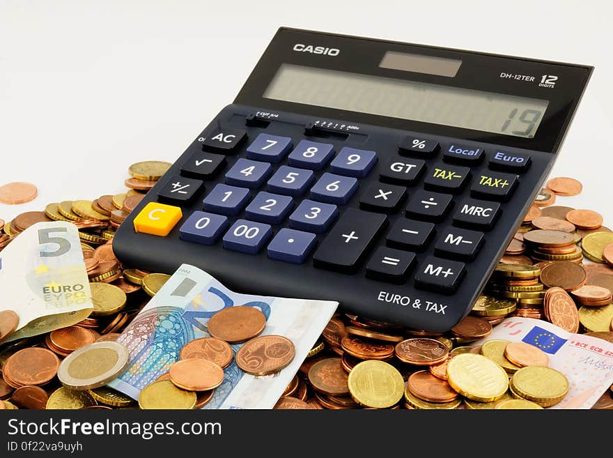 Calculator on pile of Euro coins and banknotes with white background and copy space. Calculator on pile of Euro coins and banknotes with white background and copy space.