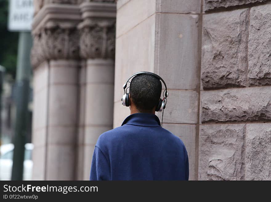 Man in Blue Long Sleeve Coat Wearing Silver and Black Headphones during Daytime