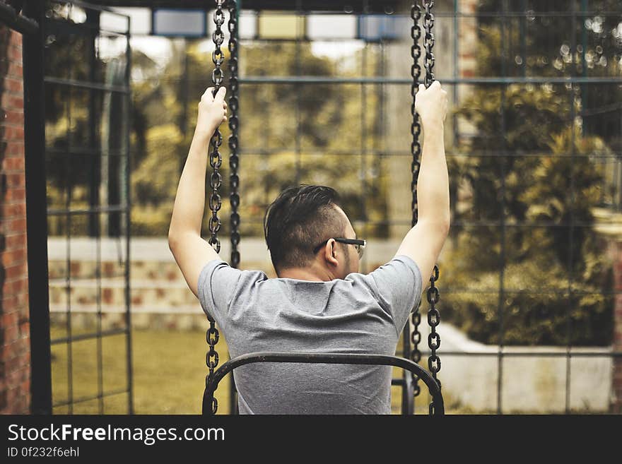 A man sitting in a swing on playground. A man sitting in a swing on playground.