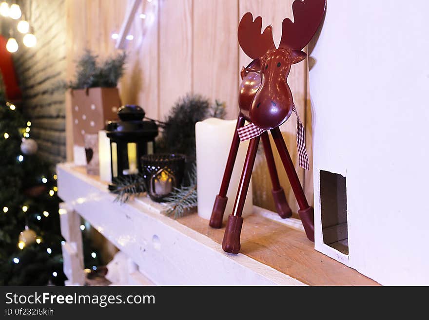 A shelf in the room with various Christmas decorations, tree, candles, elk and other items. A shelf in the room with various Christmas decorations, tree, candles, elk and other items.