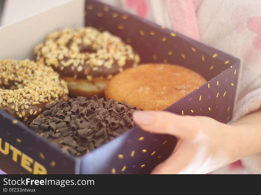 A woman holding a box of fried donuts. A woman holding a box of fried donuts.