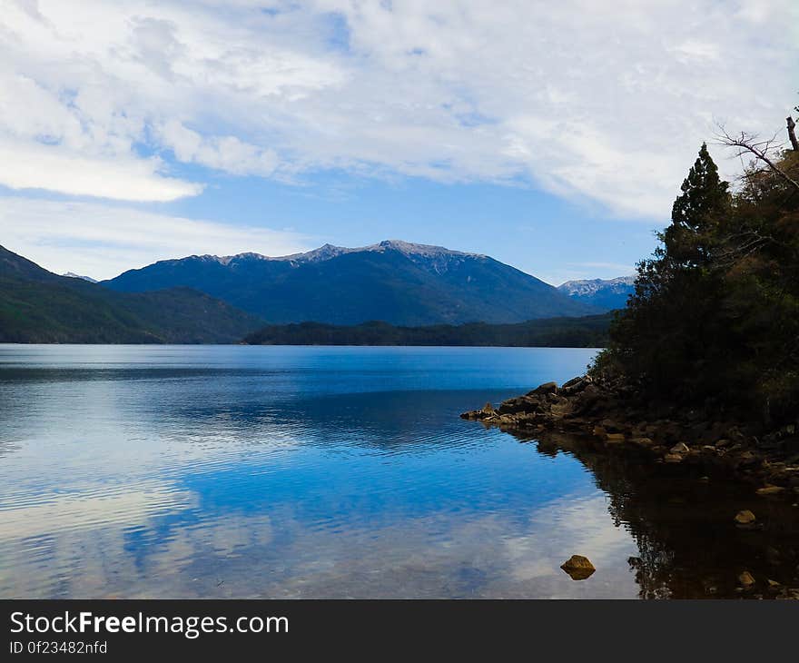 A lake with clear blue waters and mountains in the distance. A lake with clear blue waters and mountains in the distance.