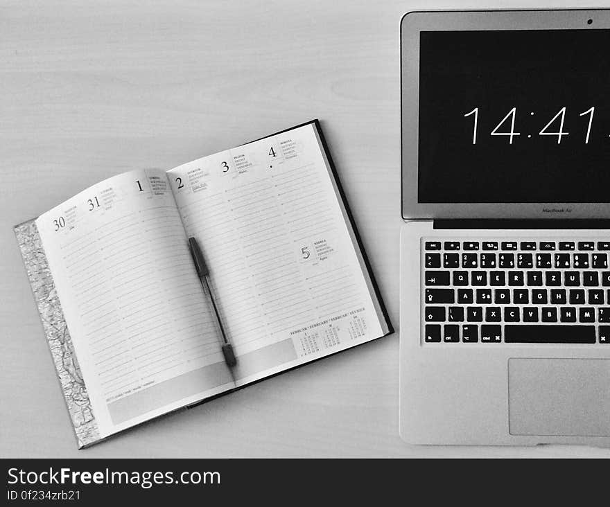 A laptop computer on the desk with an open calendar next to it. A laptop computer on the desk with an open calendar next to it.