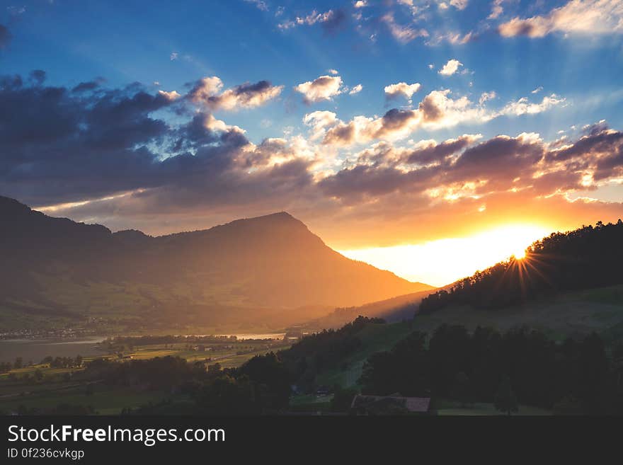 A landscape with sun setting behind mountains. A landscape with sun setting behind mountains.