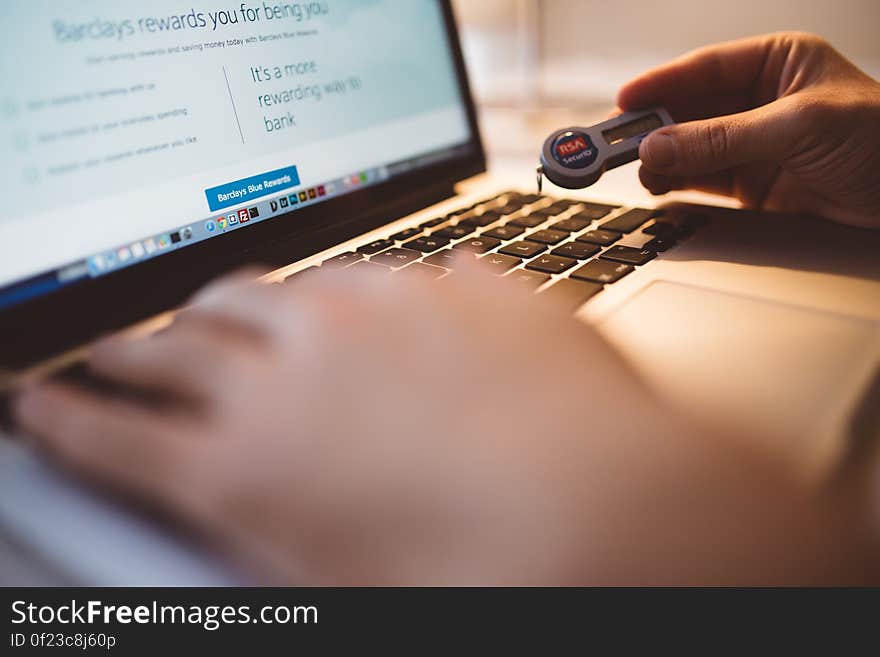 Person Holding Electronic Device While Using Its Macbook Laptop