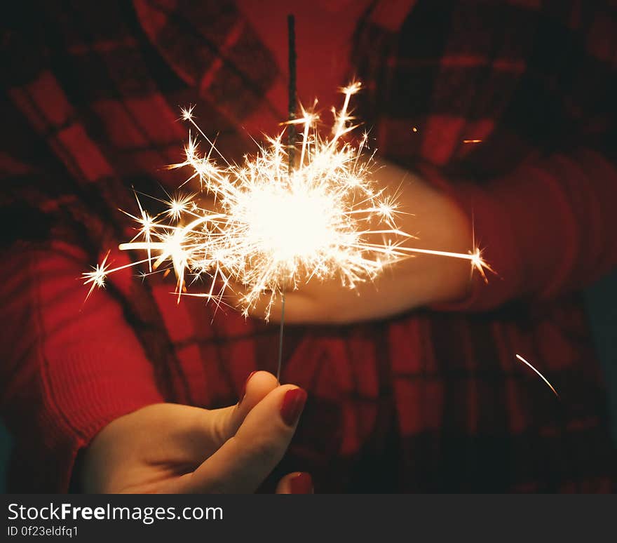 A woman holding a burning sparkler . A woman holding a burning sparkler .