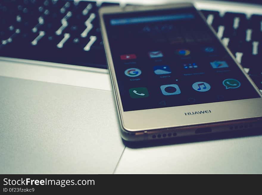 A mobile phone on top of the laptop keyboard. A mobile phone on top of the laptop keyboard.