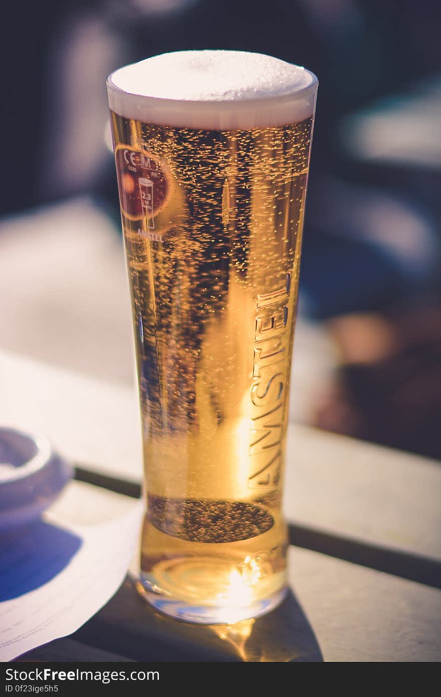 A pint of Amstel beer in a glass on table. A pint of Amstel beer in a glass on table.